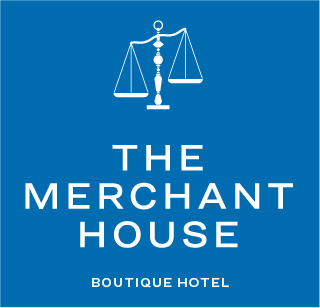 The Merchant House Manama logo — merchant's scales in white on blue