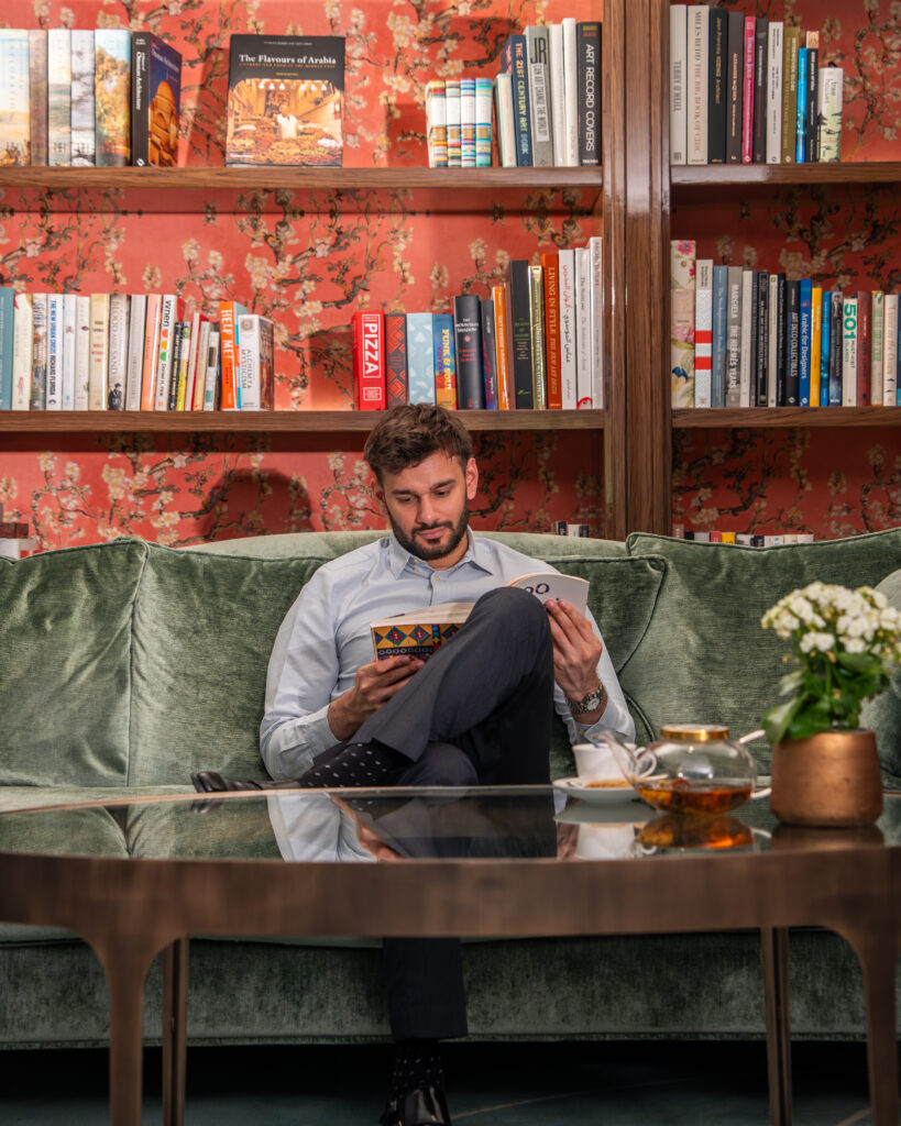 The Library lounge at The Merchant House, with coral almond-blossom wallpaper and shelves of art and design books