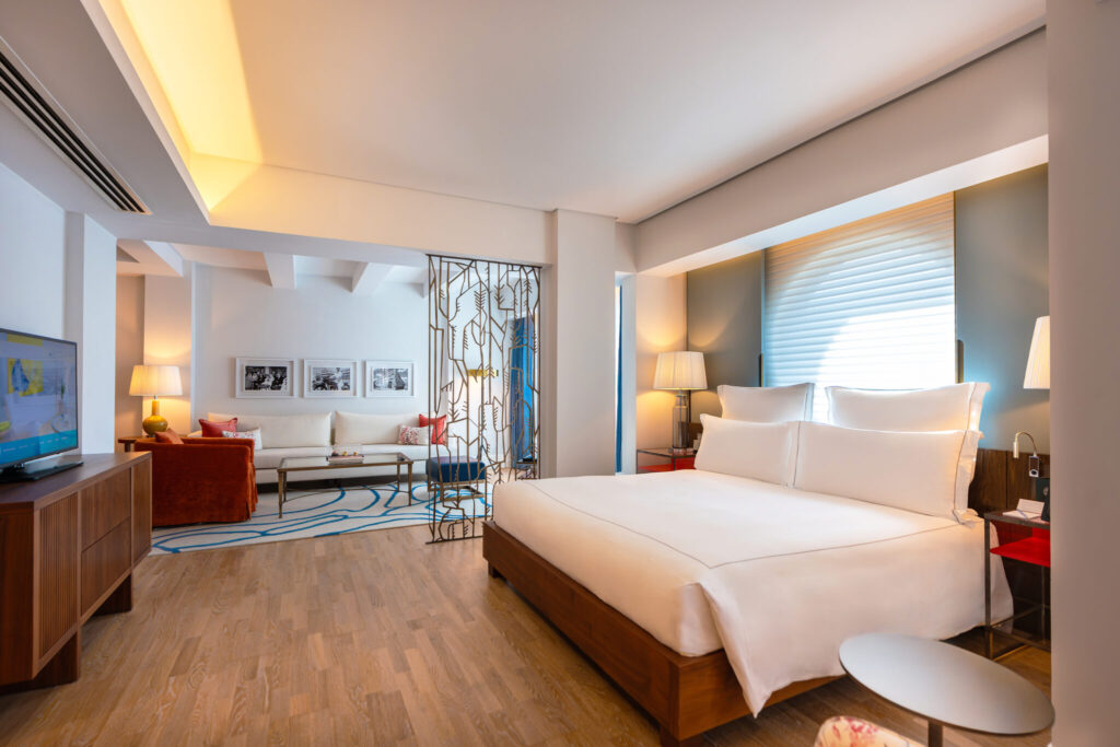 A Signature Suite at The Merchant House, Manama, with a super king bed, oak floors and a carved screen dividing the sitting room