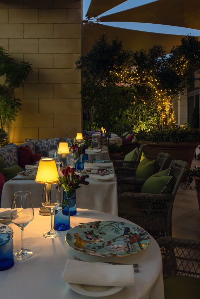 Tables set among planting on Indigo Terrace, the garden rooftop at The Merchant House, Manama